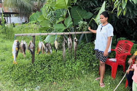 Moluccas, Halmahera: Woman sells fish at the road side