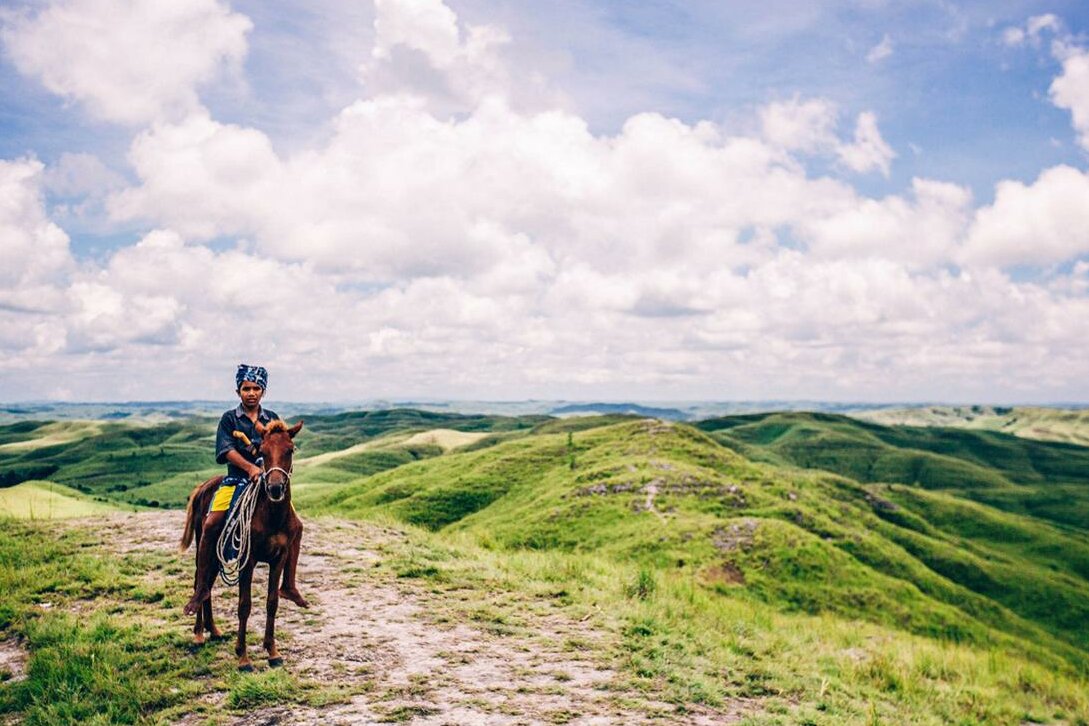 Rider on horseback in the Sumba savannah; Lesser Sunda Islands, Indonesia