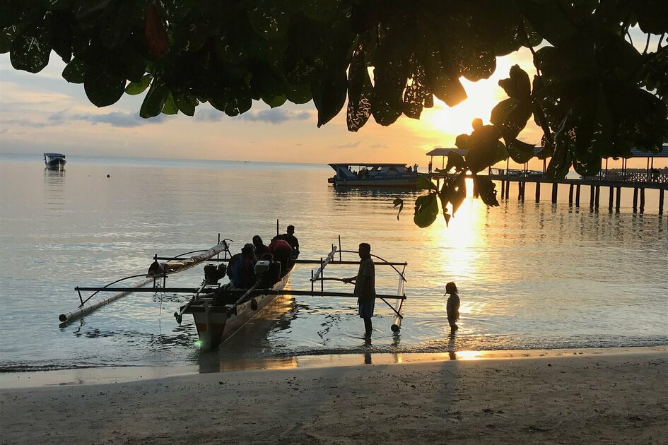 Sulawesi - Bunaken Marine Park: Small wooden boat with people at sunset