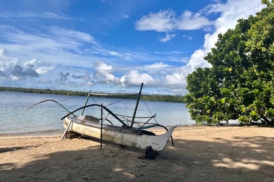 Moluccas, Halmahera: Little white wooden boat on Kupa-Kupa Resort beach