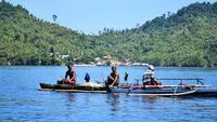 Halmahera, Indonesia: Three fishermen in wooden boat