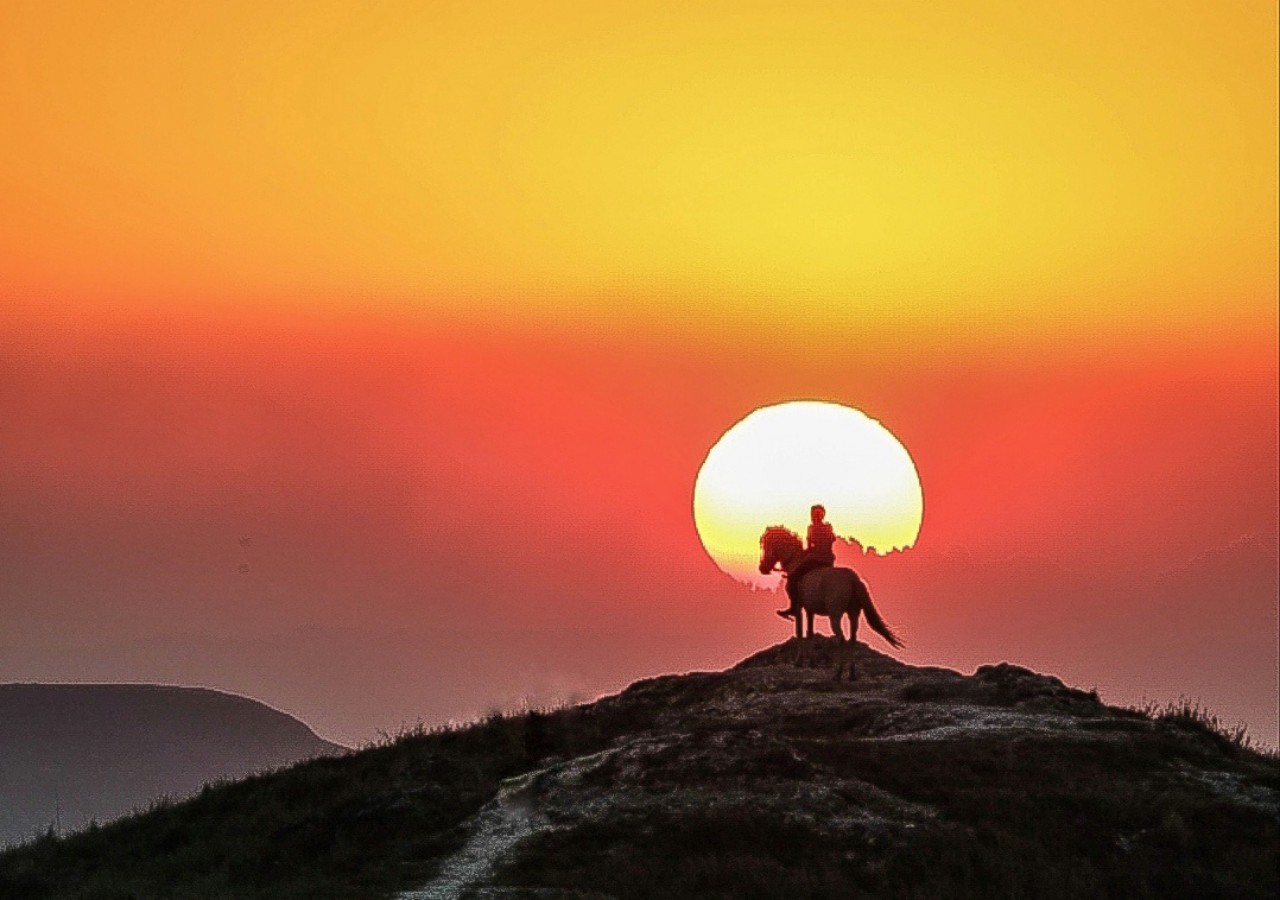 Indonesien, Insel Sumba: Reiter auf Hügel bei Sonnenuntergang